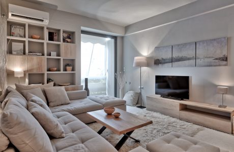 Modern, minimalist living room with built-in shelving, large TV, and wooden coffee table.