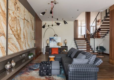 Expansive open-concept living space with marble accent wall, suspended lighting, and modern decor.