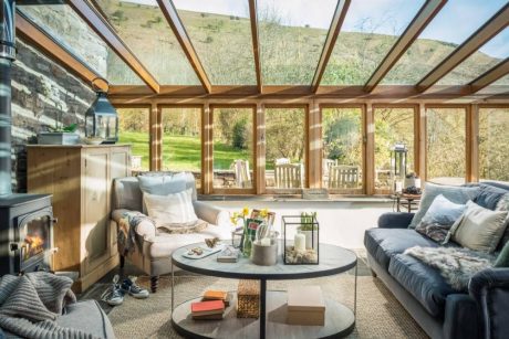 Cozy cabin living room with wood-framed glass walls overlooking scenic outdoors.