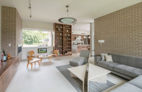 Open-concept living room with modern brick walls, shelving, and furniture.