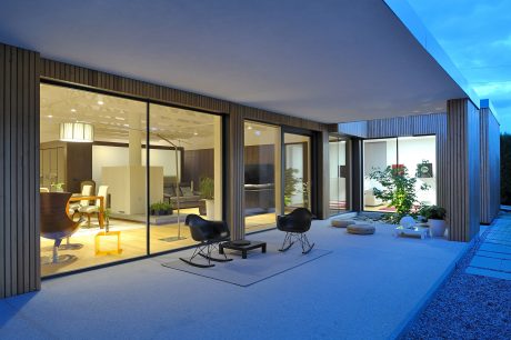 Contemporary home with floor-to-ceiling glass walls, wooden exterior, and modern furniture.