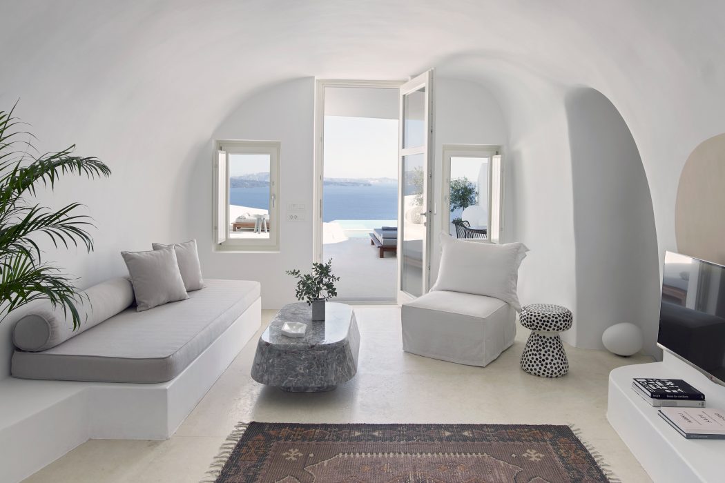 Minimalist living room with arched windows, gray furniture, and a patterned rug.