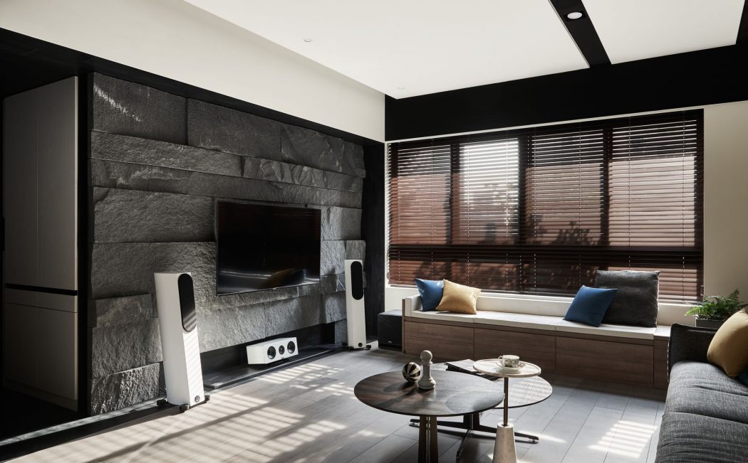 Modern living room with sleek black and wooden accents, built-in TV display, and cozy seating.
