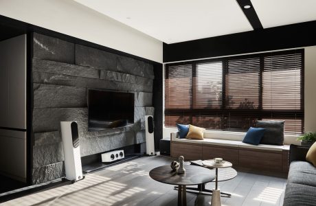 Modern living room with sleek black and wooden accents, built-in TV display, and cozy seating.