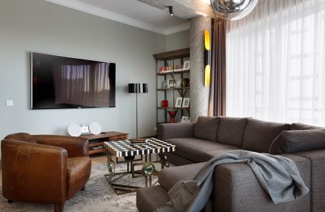 Spacious living room with wooden furniture, contemporary decor, and a large TV on the wall.