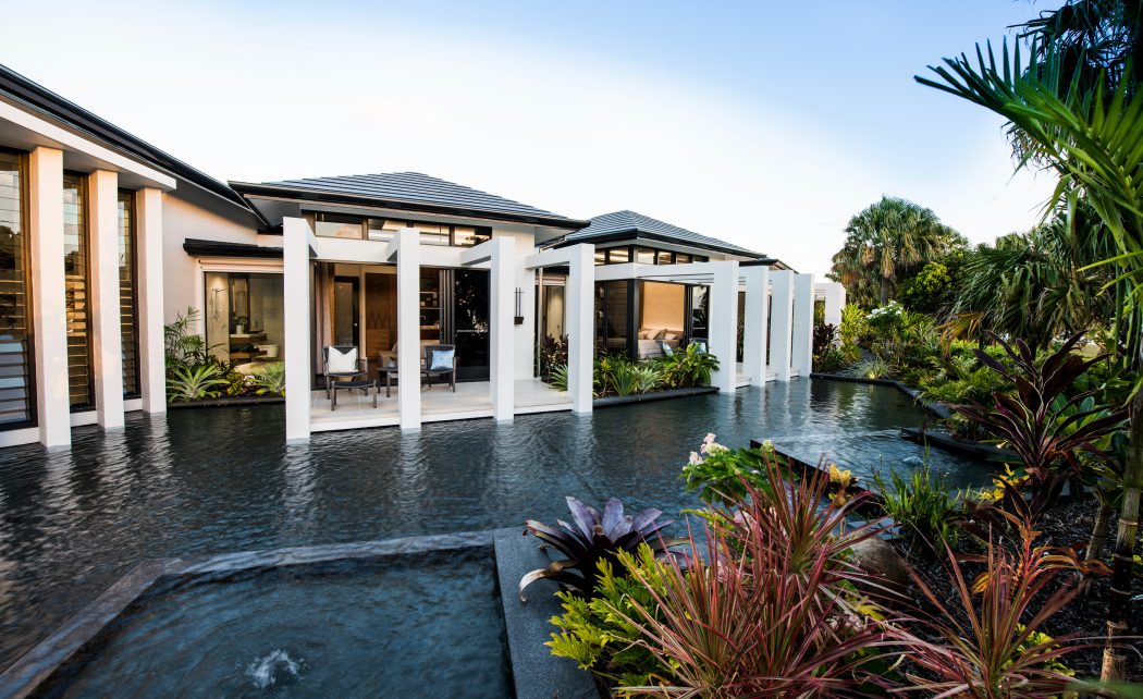 Luxurious tropical villa with modern architectural elements, reflecting pool, and lush garden.