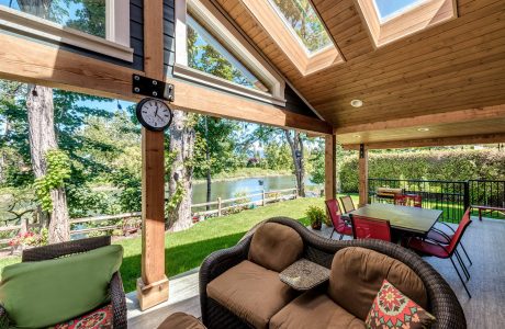 Rustic wooden pavilion with vaulted skylights, outdoor seating, and garden view.