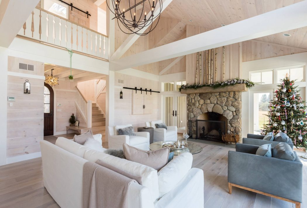 A cozy and rustic living room with stone fireplace, wooden beams, and holiday decor.