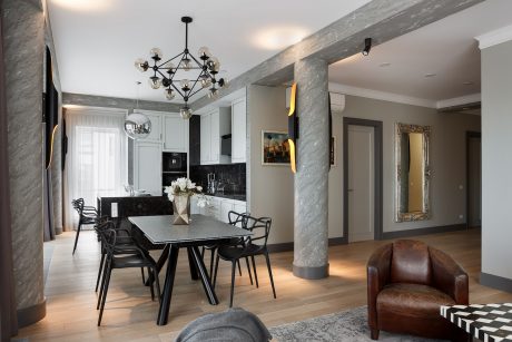 Spacious open-concept living area with elegant chandelier, marble columns, and modern furnishings.