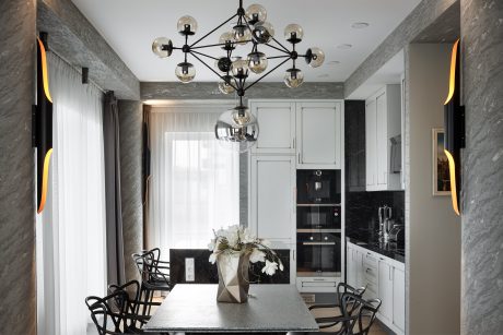 Luxurious modern kitchen with sleek appliances, ornate chandelier, and marble surfaces.