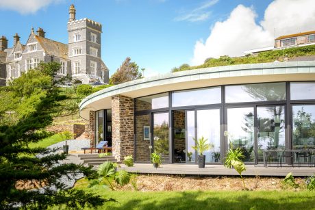 A modern glass-and-stone structure complements the historic castle-like building in the background.