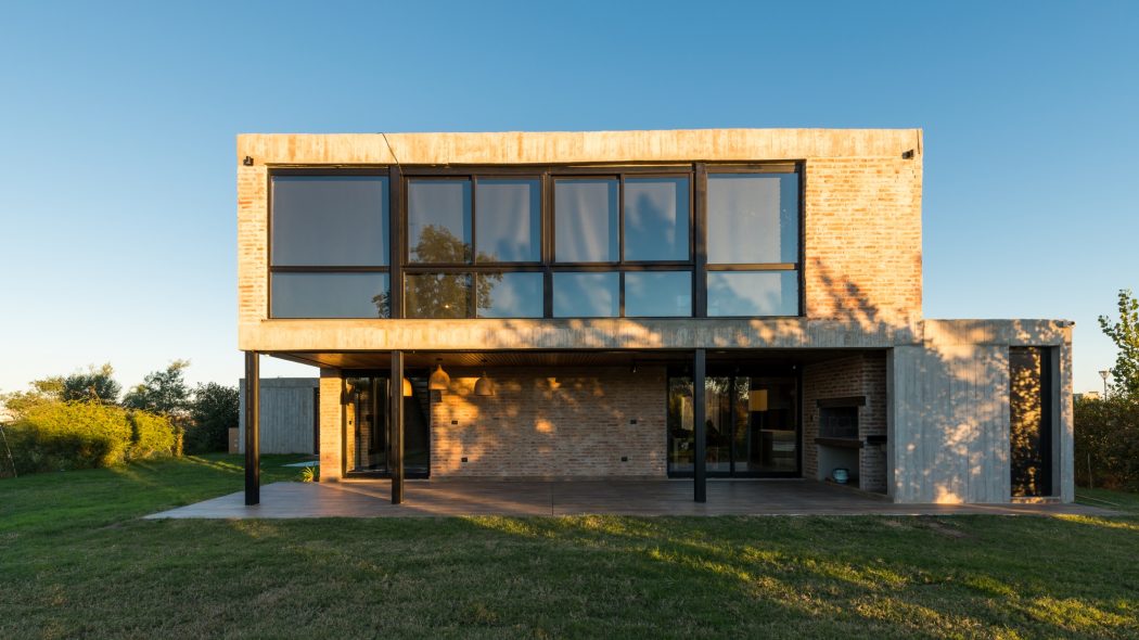 Modern brick and glass facade with large windows overlooking a grassy yard. Architectural details.