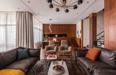 Luxurious living room features wooden walls, modern chandelier, and plush seating.