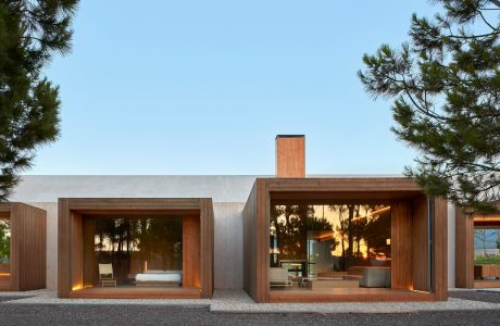 Contemporary architecture with wooden frames, open spaces, and glass walls reflecting the surrounding forest.