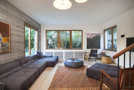 Cozy living room with concrete walls, large windows, and modern furniture layout.