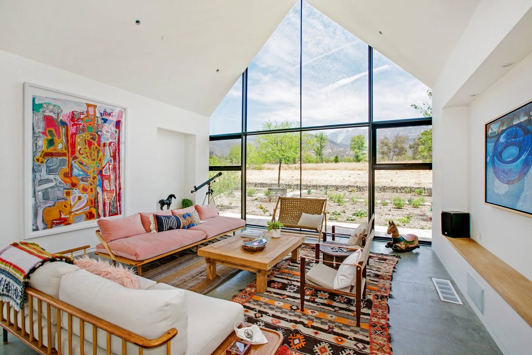 Spacious living room with high ceilings, large windows, and colorful, eclectic decor.
