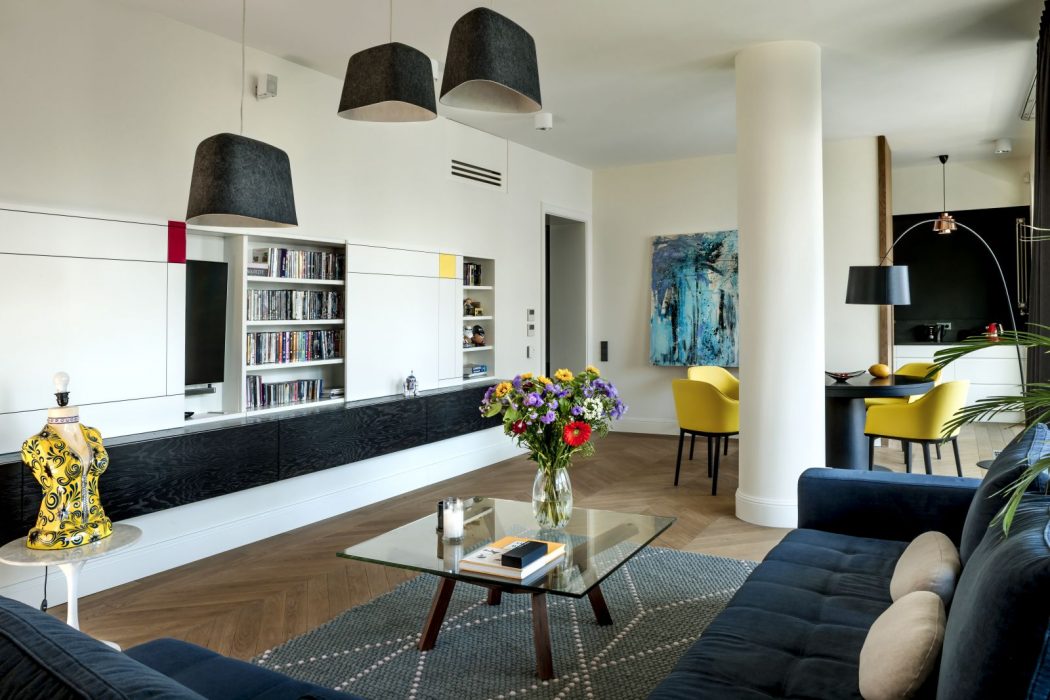 Modern living room with sleek black and white cabinetry, hanging pendant lights, and colorful accents.