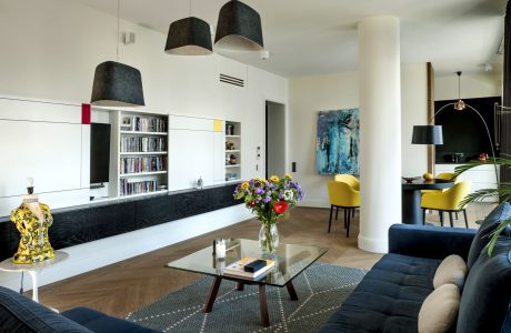 Modern living room with sleek black and white cabinetry, hanging pendant lights, and colorful accents.