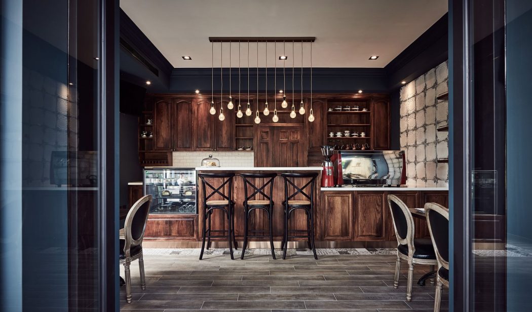 A cozy, rustic kitchen with dark wood cabinets, pendant lights, and stylish bar stools.