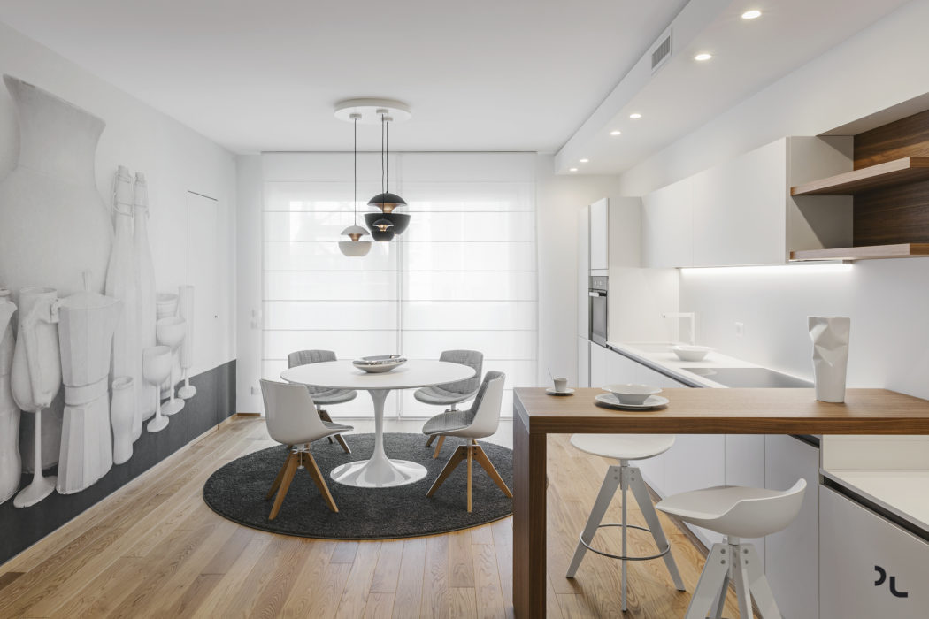 A modern, minimalist open-concept kitchen and dining area with sleek furnishings.