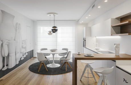 A modern, minimalist open-concept kitchen and dining area with sleek furnishings.