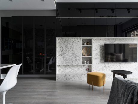 Contemporary open-plan living space with sleek, dark cabinetry, marble accents, and minimalist furnishings.