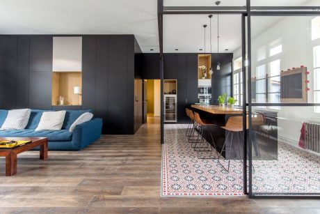 Contemporary open-plan living space with sleek black cabinetry, patterned tile floor, and industrial-style furniture.