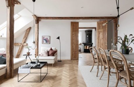 Spacious loft with exposed wooden beams, herringbone flooring, and cozy furnishings.