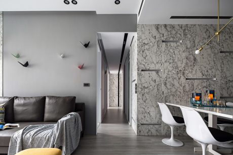 A modern apartment interior with gray walls, marble accents, and sleek furniture.
