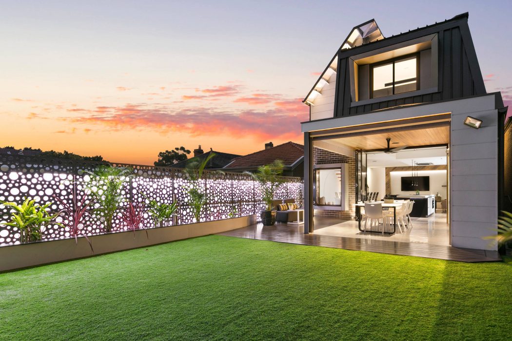 Contemporary home with modern design, large windows, and landscaped backyard at sunset.