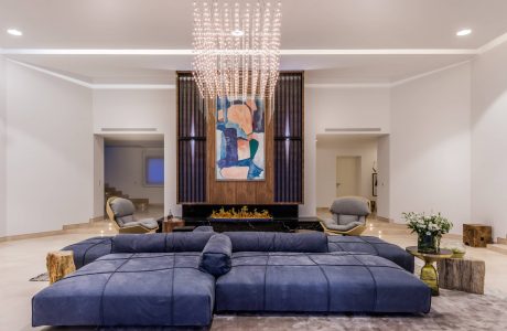 Luxurious living room with ornate crystal chandelier, marble fireplace, and plush navy sofa.