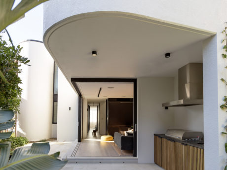 Spacious contemporary entrance with curved overhang, recessed lighting, and built-in kitchen.