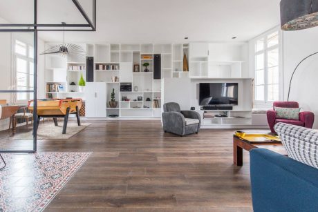 Spacious, bright living room with wooden floors, built-in shelving, and mix of modern and vintage furniture.