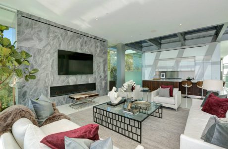 Modern, open-concept living room with sleek, minimalist furniture, marble fireplace, and glass walls.