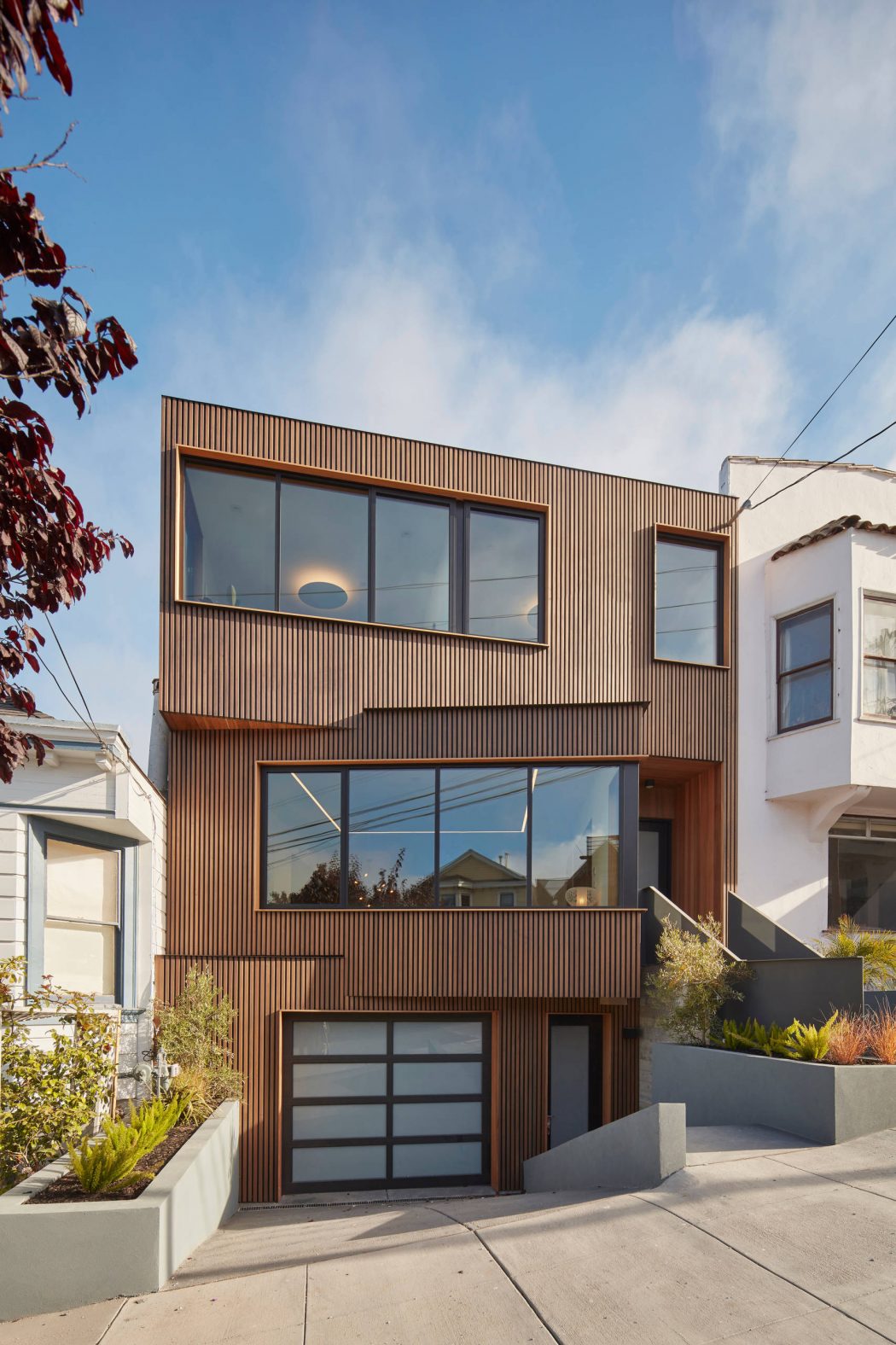 Modern multistory building with wood-paneled exterior, expansive windows, and minimalist landscaping.