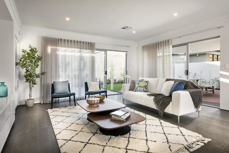 A spacious modern living room with large windows, plush seating, and textured decor elements.