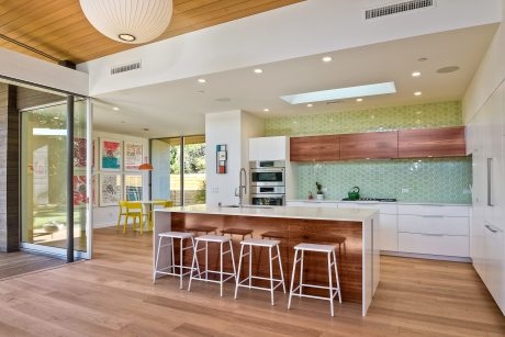 Spacious modern kitchen with hexagonal tiled backsplash, wood cabinetry, and island seating.