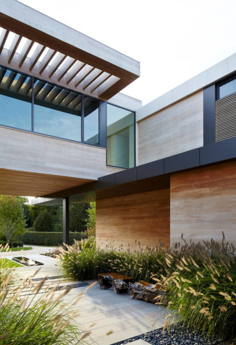 Contemporary exterior with wooden canopy, glass walls, and landscaped garden.