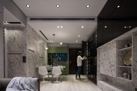 A modern, minimalist interior with marble walls, white furniture, and recessed lighting.
