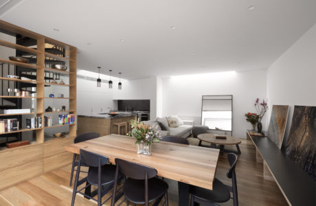 Bright, open-concept living space with wooden dining table, built-in shelves, and mid-century furnishings.