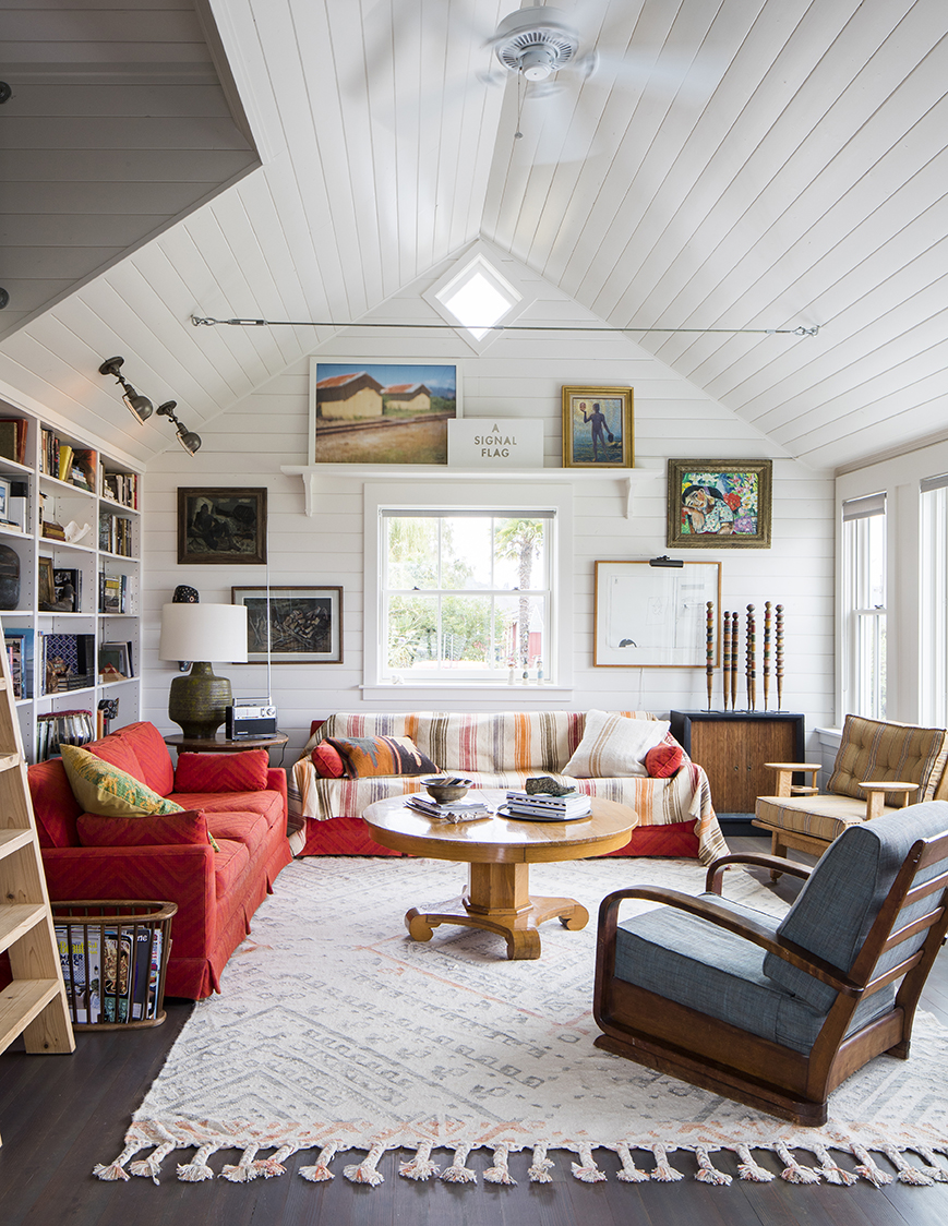Cozy living room with wooden beams, colorful furnishings, and eclectic artwork.