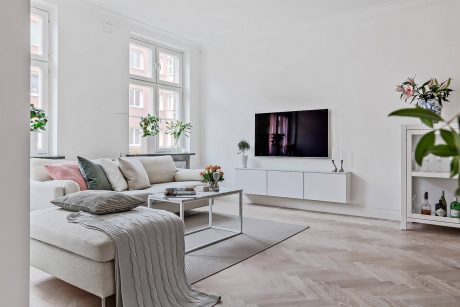 A stylish living room featuring a modern TV stand, lush potted plants, and a cozy sofa.