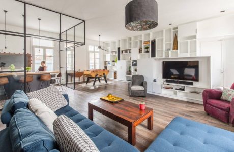 Sleek, modern open-concept living space with wood floors, built-in shelving, and statement lighting.