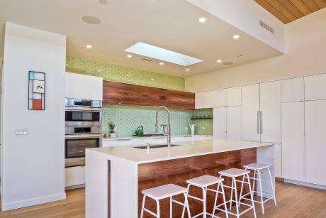 Bright modern kitchen with wooden accents, hexagonal tile backsplash, and stylish seating.
