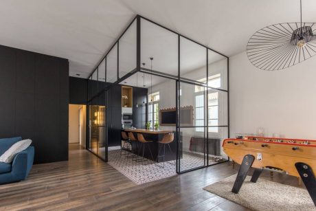 An open-concept interior with sleek black cabinets, a modern circular pendant light, and a foosball table.