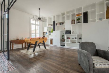 Bright, modern living room with built-in shelving, wood floors, and a retro gaming table.