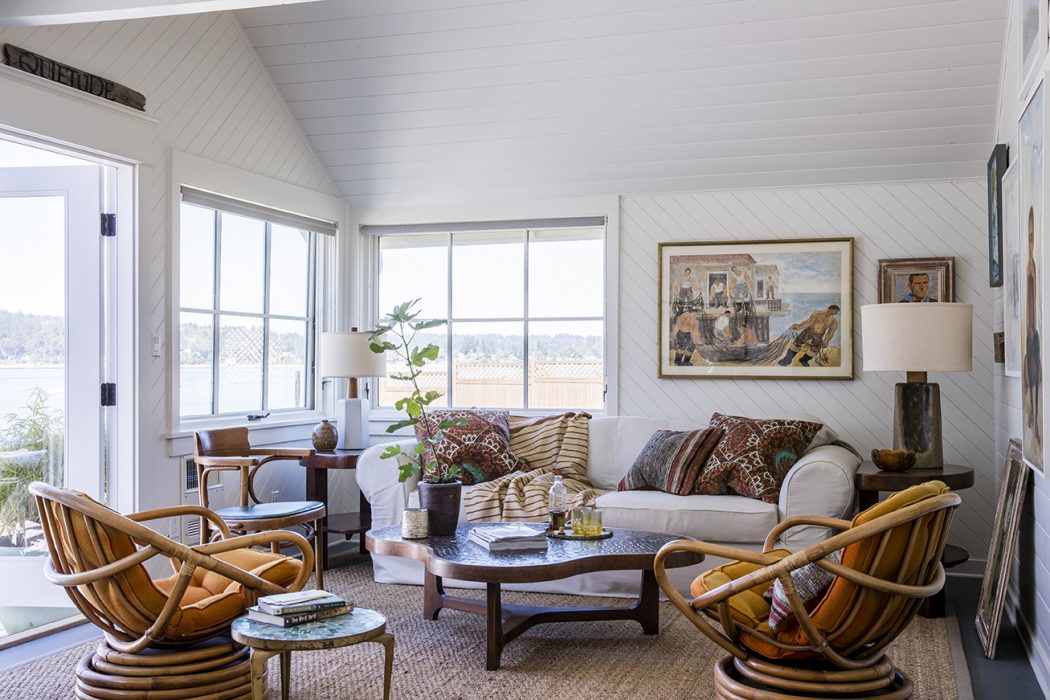 Cozy, rustic living space with vaulted ceiling, large windows, and eclectic furnishings.