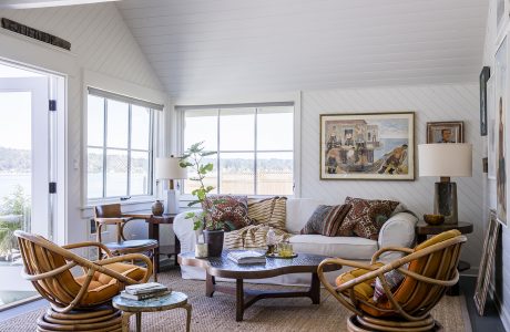 Cozy, rustic living space with vaulted ceiling, large windows, and eclectic furnishings.