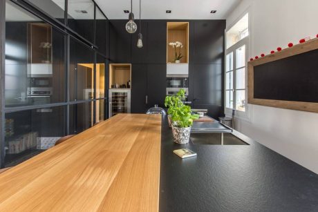 A modern kitchen with a sleek wooden countertop, black cabinetry, and stylish lighting fixtures.