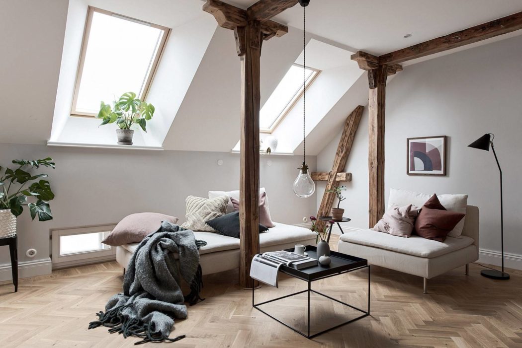 Open-concept attic living space with exposed wood beams, large windows, and modern decor.